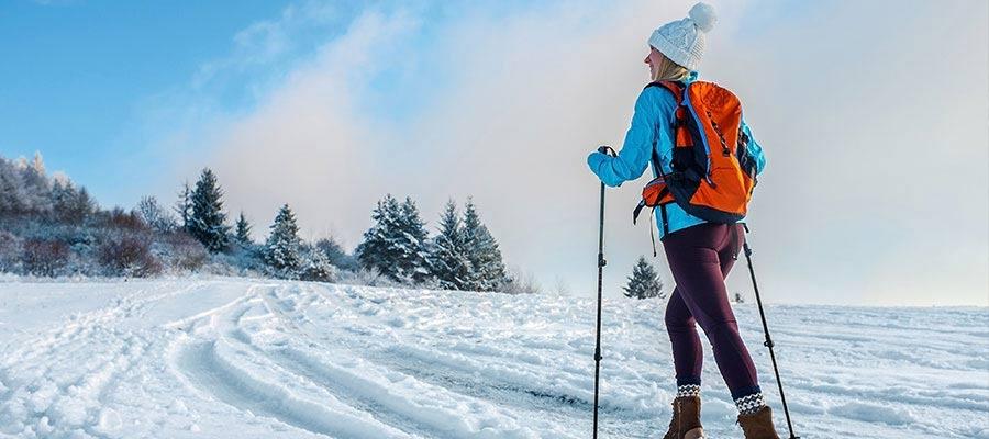 Una joven realizando esquí subiendo una colina de nieve.